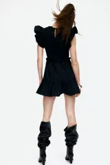 Vestido corto negro con cuerpo superior de tejido a rayas horizontales en blanco y negro, falda de popelina con volados y mangas cortas con volados.