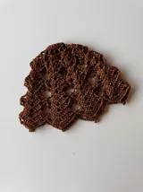 Casquete tejido a crochet en hilo metalizado color gris plata, con diseño calado.