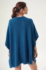 Poncho azul con cuello redondo y terminación desflecada.