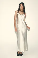 Vestido largo color blanco hueso de satén, con escote en V y tirantes finos negros ajustables en la espalda.