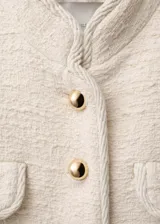 Chaqueta de tweed color crudo con cuello mao, cuatro bolsillos frontales con solapa y botones dorados.