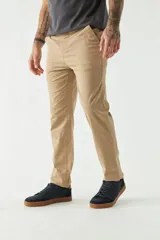 Pantalón chino color beige, de corte slim, con bolsillos laterales y traseros. Se ajusta a la cintura con cinturón de cuero marrón.