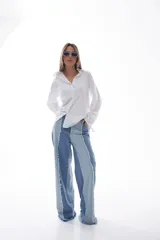 Camisa blanca de algodón con cuello clásico, mangas largas con puños fruncidos y cierre de botones al frente. Presenta frunces y lazo ajustable en la espalda.