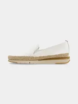 Zapato tipo slip-on de color blanco con elásticos laterales para facilitar el calce. Presenta una suela de plataforma con detalle de yute trenzado en el contorno y base de goma en tonos beige.