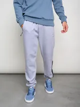 Pantalón de jogging gris melange con puños elásticos, corte slim fit y detalles en negro en los laterales. Logo de Umbro bordado en el muslo izquierdo.
