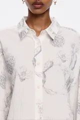 Camisa blanca con estampado de cactus en color gris, corte boxy, cuello camisero, manga larga con puño y cierre frontal con abotonadura.