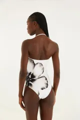 Traje de baño entero blanco con estampado de flor negra, sin tirantes, con escote en V discreto y detalle central.
