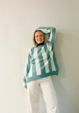 Sweater tejido a rayas horizontales anchas en color celeste y blanco, con sutil brillo. Diseño amplio y cómodo.