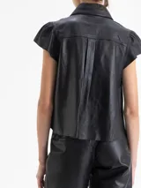 Camisa de cuero ovino negra, con volados en el centro delantero, mangas con volumen fruncidas en la copa y broches forrados en cuero.