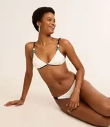 Bikini de microfibra texturizada color blanco, con corpiño triangular y bombacha colaless con laterales contrastantes y adornos de resina.