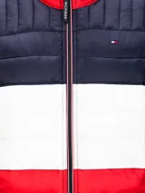Chaqueta acolchada Tommy Hilfiger con diseño a bloques de color azul marino, blanco y rojo. Tiene cuello alto, cierre de cremallera, dos bolsillos delanteros con cremallera y logo bordado en el pecho.