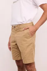 Bermuda de gabardina color verde oliva, con bolsillos laterales y traseros. Cierre frontal con botón y cremallera.