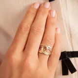 Anillo dorado con diseño de nudo entrelazado y detalles de circonias. Fabricado en oro 10k.