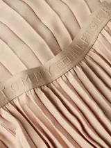 Falda midi plisada color beige con cintura elástica con logo de Tommy Hilfiger repetido.