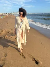 Túnica larga de gasa color beige claro, con mangas largas y cuello en V, con detalle de amarre frontal.