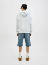 Buzo con capucha celeste, de manga larga y fit loose. Confeccionado en tejido loop back cepillado por dentro, con mangas ranglán, puños de canalé, forro de la misma tela en el interior de la capucha y estampa en goma de tacto suave ubicada en la espalda.