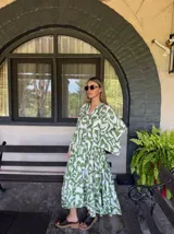 Vestido largo de corte amplio con estampado abstracto en tonos verde y blanco, escote en V y mangas largas acampanadas. Cierre frontal con botones. 