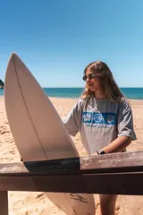 Remerón cropped gris con estampado de motivos playeros en azul y texto "Glassy Waves".