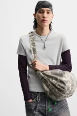 Bolso de hombro color gris con efecto desgastado, fabricado en tejido de algodón. Tiene un compartimento principal con cierre de cremallera, un bolsillo interior con cremallera y asa de hombro ajustable.