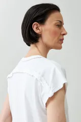 Remera color durazno con cuello en V y detalle de trenza en el escote.