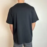 Remera negra de corte oversize con estampado rectangular de palmeras en el pecho.