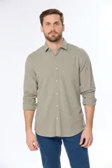 Camisa de lino color beige, de manga larga, con cuello clásico y bolsillo en el pecho.
