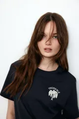 Remera negra de corte holgado en punto de algodón con cuello redondo y estampado de palmera con texto en el frente.