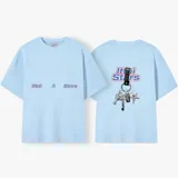 Camiseta celeste con estampado frontal de la frase "Ittai Stars" y una estrella. En la parte posterior tiene un estampado de un llavero con llaves y dijes.