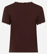 Blusa de algodón con textura acanalada en color blanco, de manga corta y cuello redondo. Presenta un acabado ondulado tipo festón con borde contrastante en color negro tanto en el cuello como en los puños de las mangas.