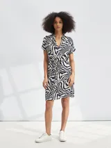 Vestido corto con estampado animal print de cebra en blanco y negro, con cuello en V y lazo en la cintura.