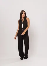 Mono largo negro de punto con escote halter y corte palazzo. Incluye un collar largo con dijes de estrellas plateadas.
