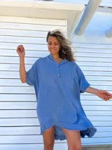 Túnica celeste de lino rústico, corte holgado, cuello en V con botones y ruedo irregular con flecos.