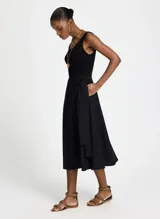 Vestido midi negro sin mangas, con corte evasé, cuello redondo y bolsillos laterales.