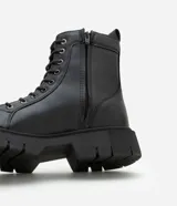 Bota de caña media color negro, estilo coturno, con cordones y cierre lateral. Suela track.