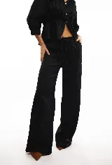 Pantalón de lino negro, corte amplio, con cintura elastizada y cordón de ajuste.