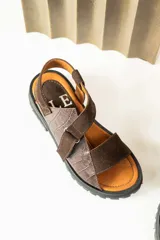 Sandalias de cuero color marrón y blanco, con suela track negra y ajuste con velcro.