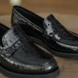 Mocasín de cuero vacuno color marrón, con detalle de antifaz en gamuza. Tiene taco de madera foliado en cuero de 2,5cm y entre suela de goma de 1cm.