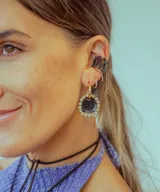 Par de aros colgantes con dije circular de resina con glitter multicolor y borde de strass. El arito es de acero quirúrgico dorado.