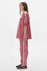 Remera oversized de denim color rosa lavado, con mangas caídas, cuello a contratono color crema y bordados en el frente.