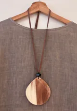 Collar con cordón de gamuza marrón regulable y dije ovalado de acrílico beteado en tonos tierra, marrón y crudo.