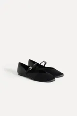Zapato tipo bailarina color negro con efecto satinado, punta redonda y tira con hebilla ajustable.