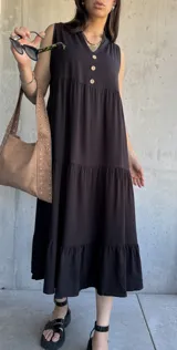 Vestido midi negro con escote en V, sin mangas, corte holgado y tres botones en la parte superior.