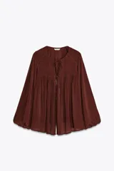 Blusa marrón con cuello redondo con cordón con abalorios, escote pico y manga larga abullonada. Cierre frontal con botones forrados a tono.