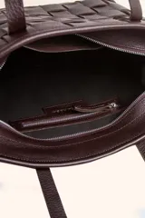 Cartera tipo tote bag de cuero vacuno trenzado a mano, con diseño de tejido ajedrez. Cuenta con doble asa de hombro y cierre superior.
