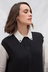 Camisa larga de lino color beige, con cuello camisero y cierre frontal con botones. Tiene mangas largas con puños abotonados, bolsillos laterales y una franja a contratono en la espalda y mangas.