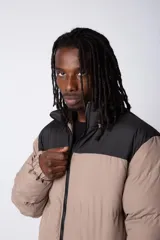 Campera puffer gris con la parte superior negra, cierre frontal y cuello alto.