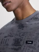 Remera gris con estampado abstracto en negro y logo de Calvin Klein en el pecho.