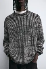 Jersey de punto negro con textura acanalada vertical, cuello redondo y manga larga.