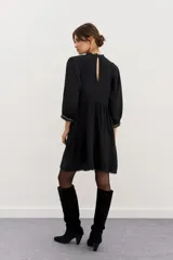 Minivestido negro de viscosa con corte en la cintura, detalles de puntillas en cuello y ruedo, gota en la espalda y pechera bordada en hilo con apliques.