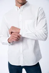 Camisa blanca de manga larga, corte clásico, con cuello abotonado y bolsillo en el pecho.